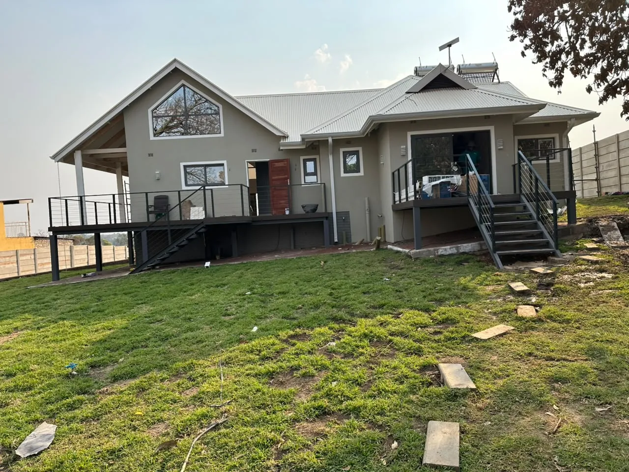 Completed grey residential building with raised decks and metal roof