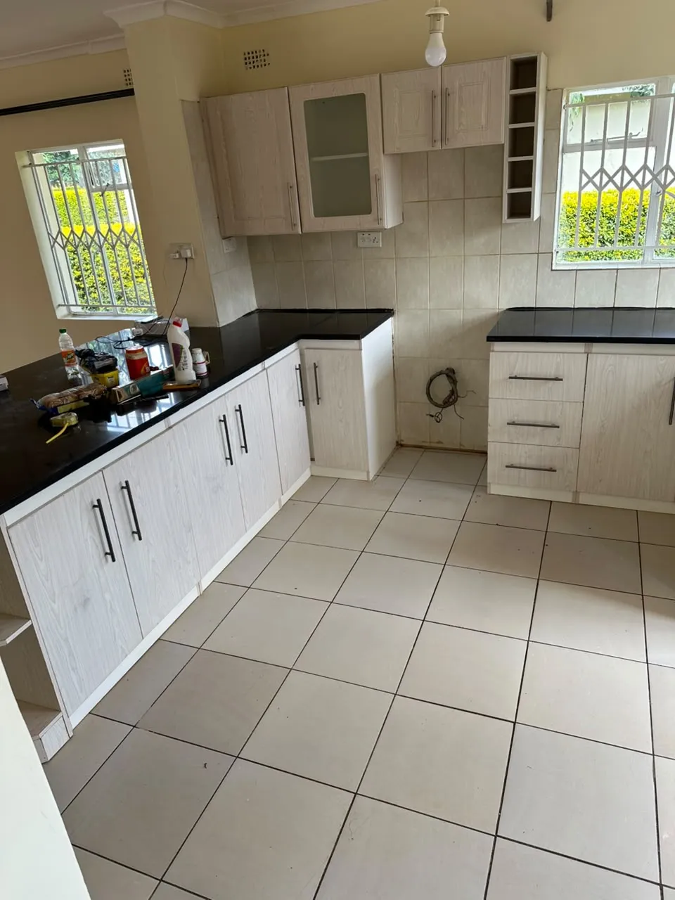 Kitchen with fitted light cabinets, dark counters and tiled walls